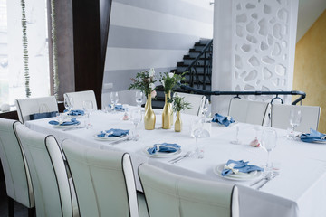 Served for wedding banquet table in blue white. Wedding decoration. Blue napkin with flower on a white plate. Golden bottles are vases for flowers.
