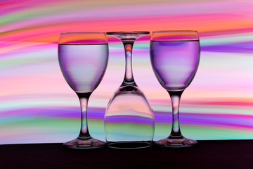 Three wine glasses in a row with colorful light painting behind