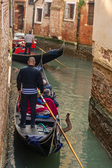 Fototapeta na wymiar Italy, Venice, view of canals with gondolas carrying visiting tourists.