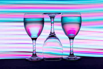 Three wine glasses in a row with colorful light painting behind