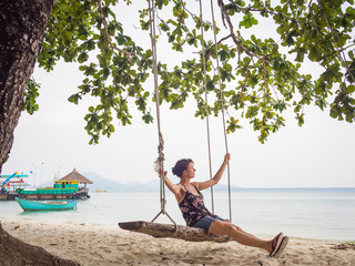 Obraz premium Caucasian woman is swinging on a wooden swing at the beach