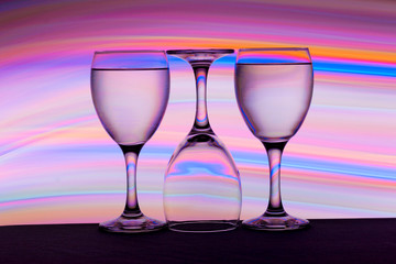 Three wine glasses in a row with colorful light painting behind