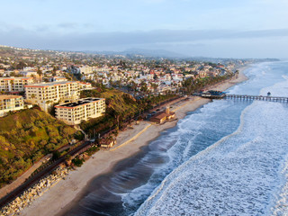 Aerial view of San Clemente Pier with beach and coastline before sunset time . San Clemente city in Orange County, California, USA. Travel destination in the South West Coast. Famous beach for surfer. - obrazy, fototapety, plakaty