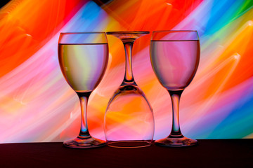 Three wine glasses in a row with colorful light painting behind