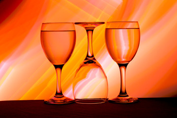 Three wine glasses in a row with colorful light painting behind