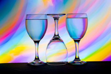 Three wine glasses in a row with colorful light painting behind