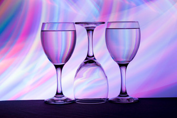 Three wine glasses in a row with colorful light painting behind