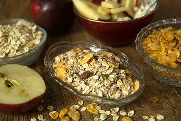 Muesli with dried fruit, Barley flake, fresh organic red apple,  and corn flakes. Close up photo of a cereal grain product and apples