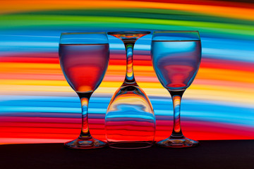 Three wine glasses in a row with colorful light painting behind