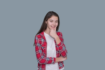 young girl smiling thoughtfully holding her chin, gray wall background