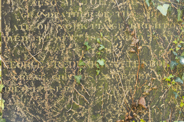 An Old Gravestone surface with text letters on it, close up