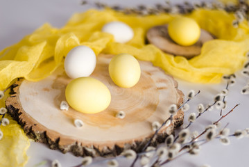 Sunny Easter photo. The photo shows willow twigs, wooden cuts, yellow and white Easter eggs.