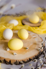Sunny Easter photo. The photo shows willow twigs, wooden cuts, yellow and white Easter eggs.