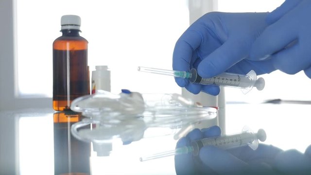 Slow Motion with Doctor Hands Protected with Special Gloves Checking a Syringe