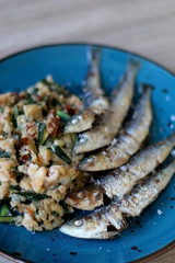 Grilled sardines and salad made with chicory, white beans and dried tomatoes. Selective focus. 