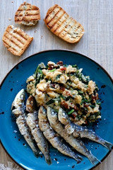 Grilled sardines and salad made with chicory, white beans and dried tomatoes. Selective focus. 