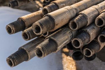 Drill pipes for drilling oil and gas wells are located horizontally on the rack. In the foreground is a threaded pipe joint. In the background is a blurred image of the other pipes.