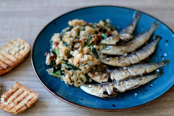 Grilled sardines and salad made with chicory, white beans and dried tomatoes. Selective focus. 