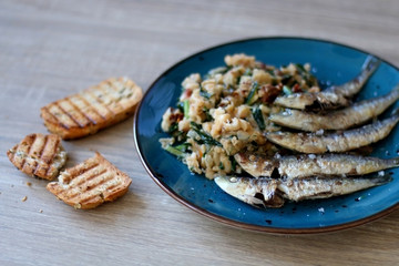 Grilled sardines and salad made with chicory, white beans and dried tomatoes. Selective focus. 