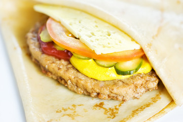 Thin delicious pancake with meat steak, cheese, tomato and cucumber on white