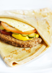 Thin delicious pancake with meat steak, cheese, tomato and cucumber on white
