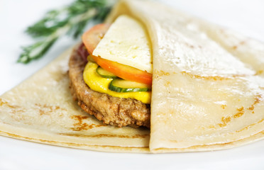 Thin delicious pancake with meat steak, cheese, tomato and cucumber on white