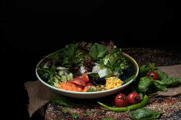 various fresh mix salad leaves with tomato in bowl on wooden background