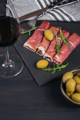 Black stone platter with slices of cured ham or Spanish jamon serrano or Italian prosciutto crudo