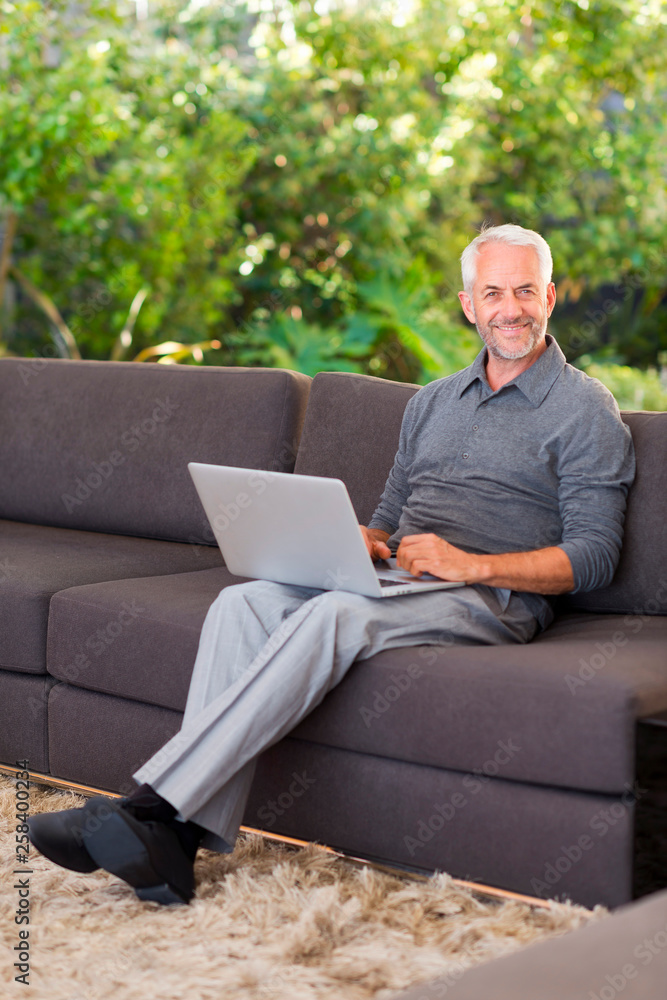 Wall mural Man surfing the web on sofa