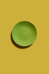 Green dish on a yellow backgroung. Deep shadow. Postcard, Design. Pace for text, copy space.