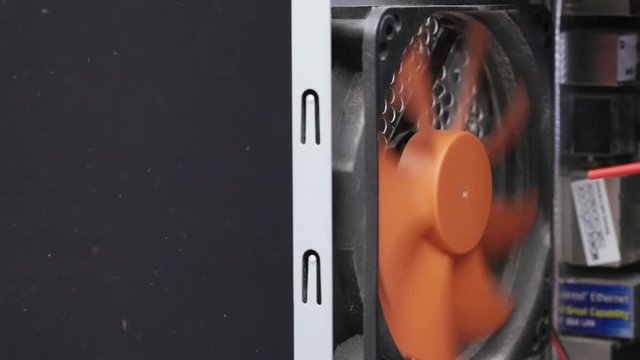 Service for repair and cleaning of computer equipment. Side view of a service worker removes dust and dirt from a PC case fan with compressed air.