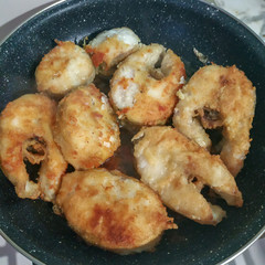 Many pieces of fish frying in a pan 