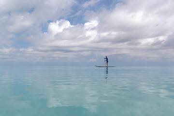 Young Adult Man with stand up paddle in clear blue water