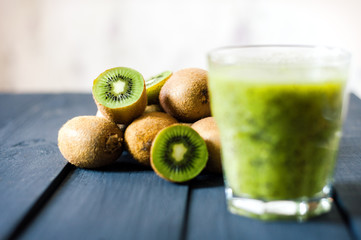 glass of kiwi juice with fresh fruits on black wooden table