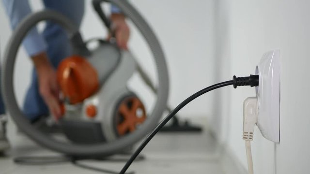 Man Using Electric Vacuum Cleaner at Home Cleaning the Floor