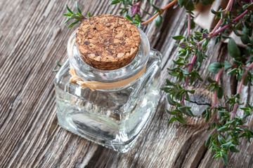 A bottle of thyme essential oil with fresh thyme twigs