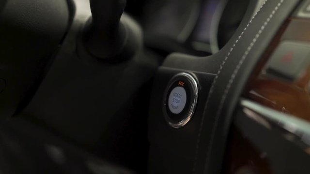 Close up for car driver starting the engine of the modern vehicle, modern technologies concept. Stock. Man finger pressing star, stop engine button.