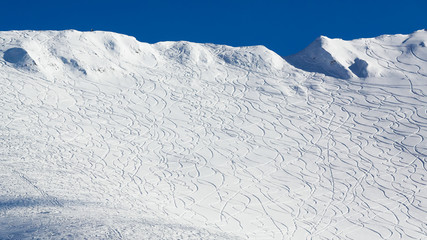Shredded snowy mountain face with many trails
