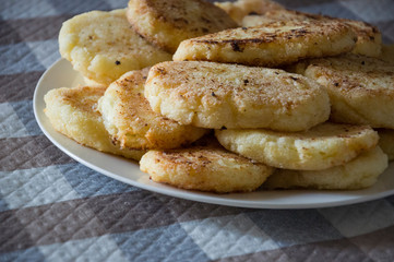 Hot tasty baked cheese pancakes in the plate standing on the  checkered tablecloth. Breakfast