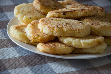 Hot tasty baked cheese pancakes in the plate standing on the  checkered tablecloth. Breakfast