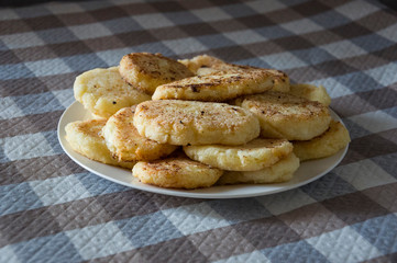 Hot tasty baked cheese pancakes in the plate standing on the  checkered tablecloth. Breakfast