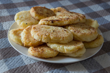 Hot tasty baked cheese pancakes in the plate standing on the  checkered tablecloth. Breakfast