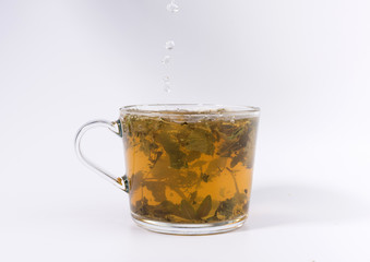 pouring hot water to the glass cup with tea, isolated on white background