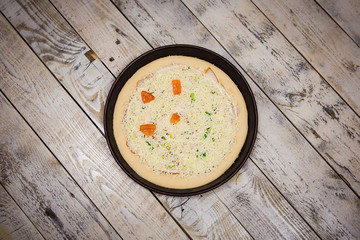 Round pizza dough is in the pan. The process of cooking pizza, stacking ingredients on the dough.