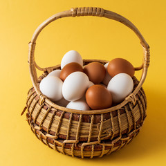 Eggs in a basket over yellow background.