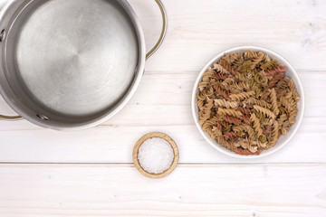 Add pasta to a pot to boil. recipe step by step fusilli pasta with zucchini with a stock pot flatlay on white wood