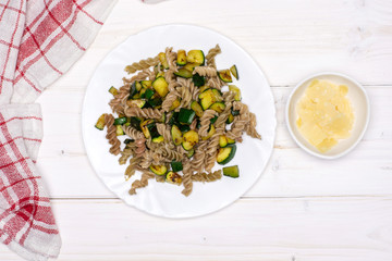 Add parmesan cheese. recipe step by step fusilli pasta with zucchini on white porcelain plate with a tea towel flatlay on white wood