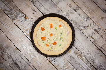 Round pizza dough is in the pan. The process of cooking pizza, stacking ingredients on the dough.