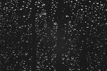 Naklejka na ściany i meble Dirty window glass with drops of rain. Atmospheric monochrome dark background with raindrops. Droplets and stains close up. Detailed transparent texture in macro with copy space. Rainy weather.