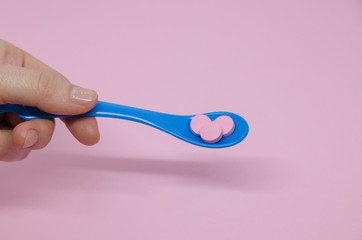 Medical pink pills in a spoon